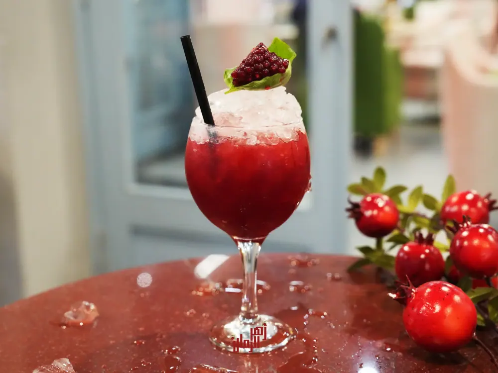 A pomegranate cocktail on a marble table, with the restaurant behind it