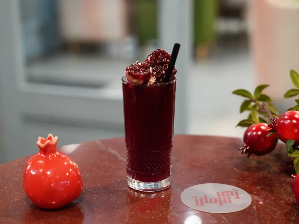 A whole pomegranate beside a glass of pomegranate juice
